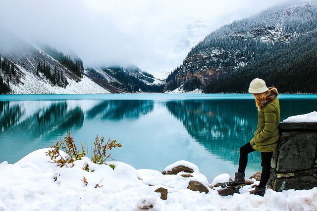 Woman beside a snowy mountain lake