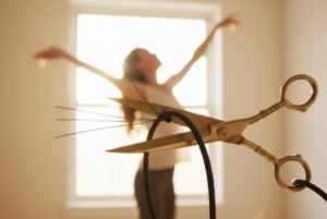 woman dancing and a scissor cutting a cord